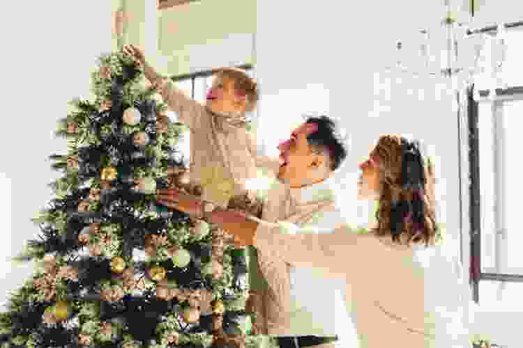 young family of three decorating their Christmas tree together