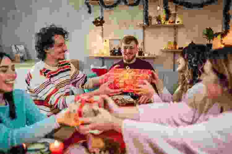 family and friends exchanging gifts around dinner table