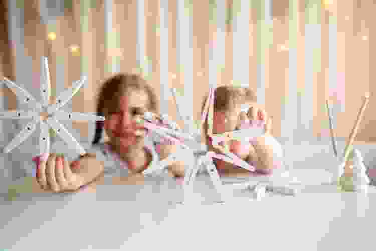young children holding handmade snowflakes made of clothing pins