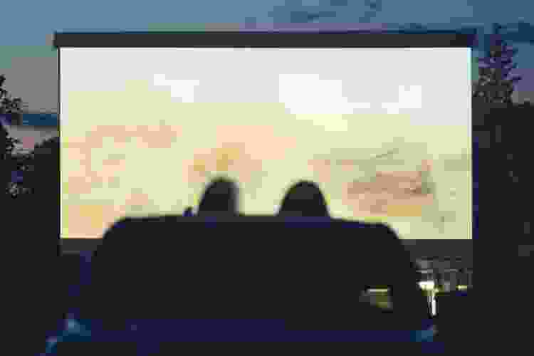 silhouette of couple watching drive-in movie screen