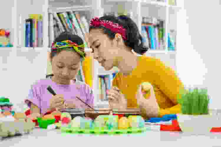 mother and young daughter dyeing Easter eggs