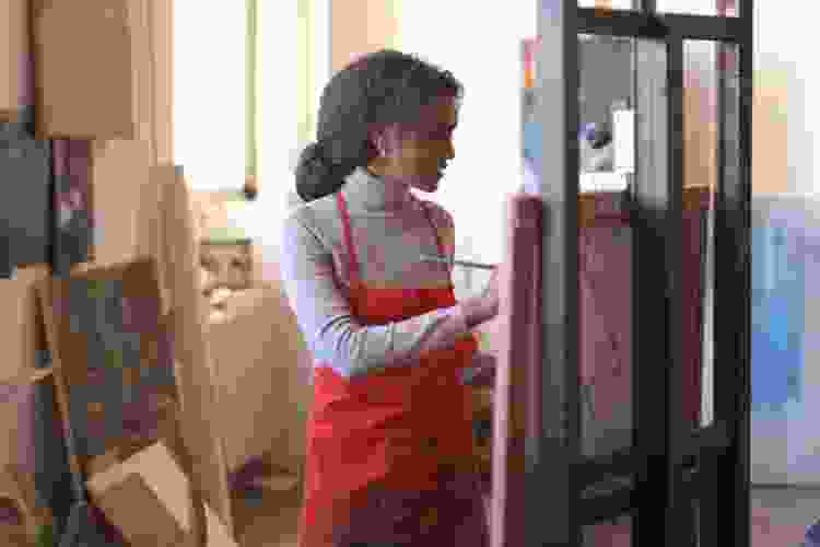 young woman painting in studio on an easel