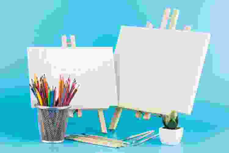 small easels on table with colored pencils and paint