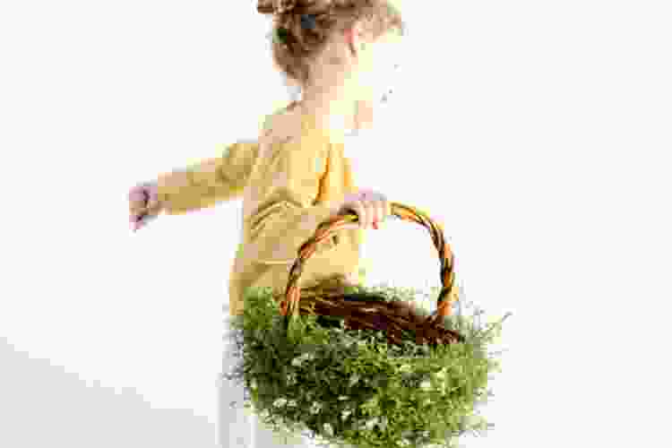 little girl running with Easter basket that is wrapped in greenery