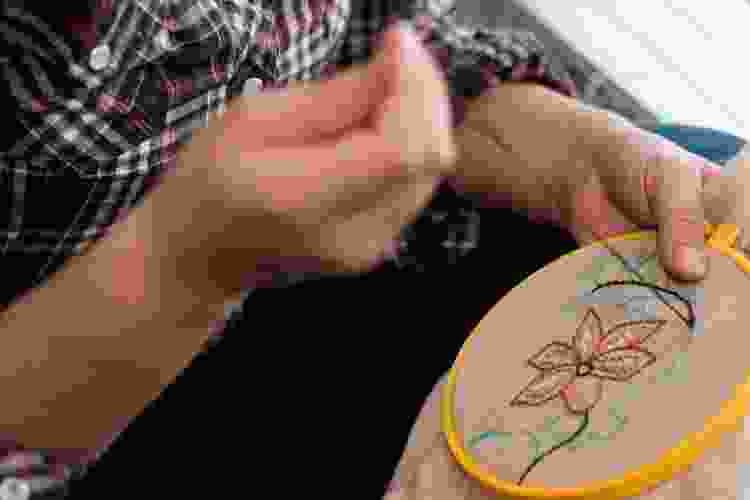 embroidering flowers into fabric