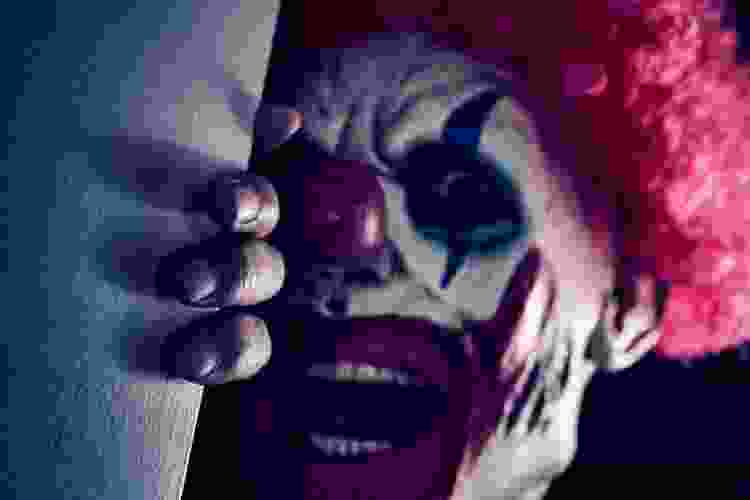 evil clown peering around a dark corner