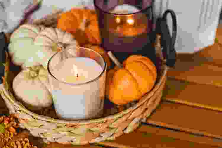 basket filled with fall scented candles and miniature pumpkins