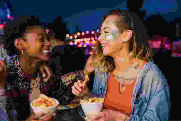 two young women eating food at festival