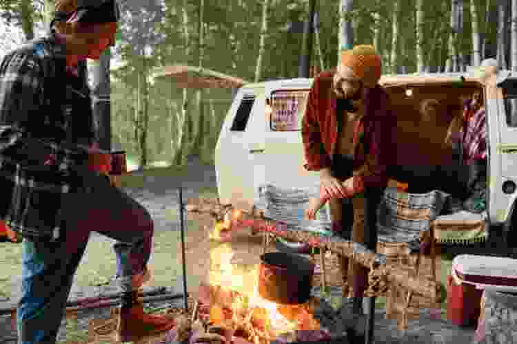 two friends cooking over campfire