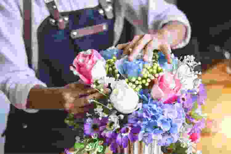 hands arranging flowers in a vase