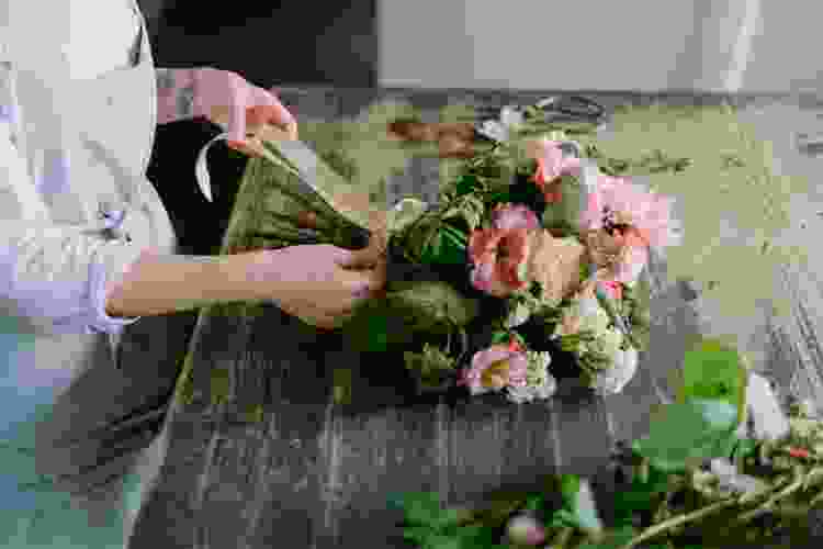 hands tying ribbon on bouquet of flowers