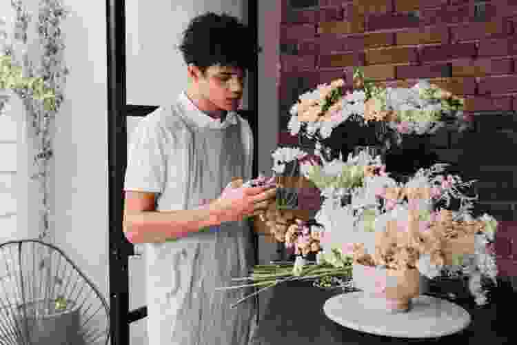 man arranging white flowers into a vase