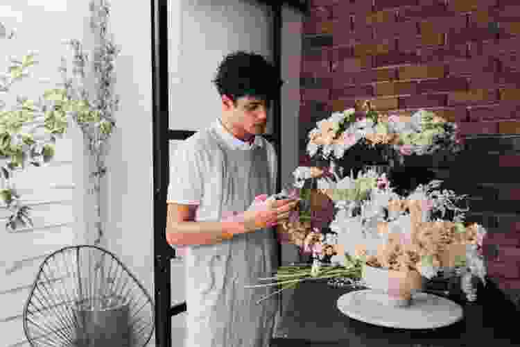 man trimming flower stems in arrangement