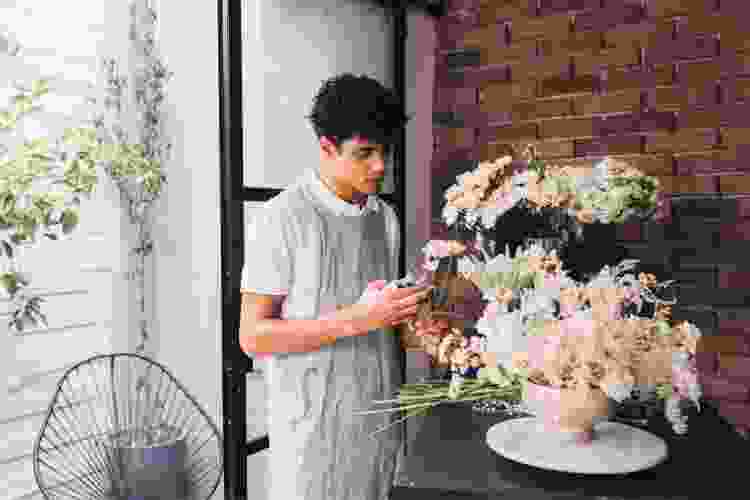 man arranging white flowers 