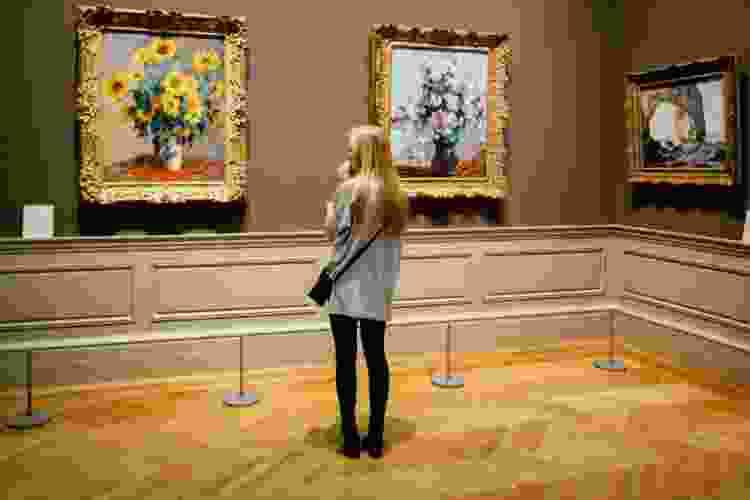 young woman viewing flower paintings in art museum