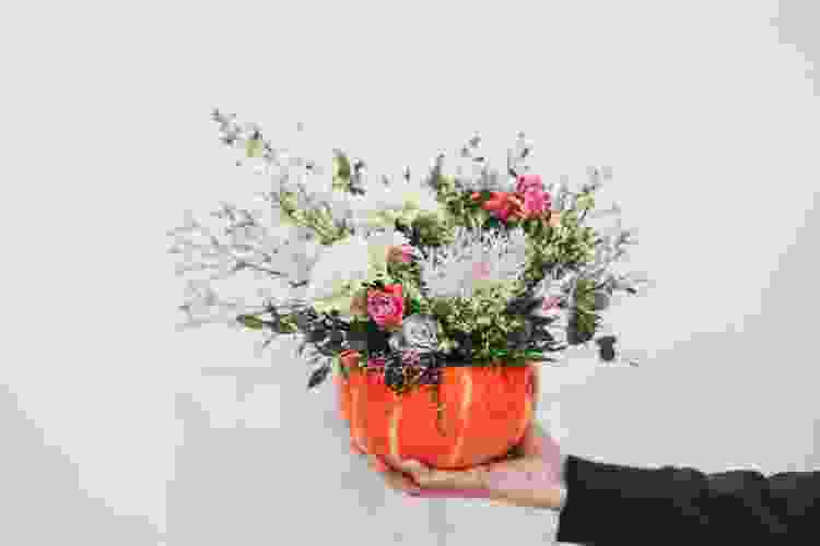 holding small pumpkin bouquet filled with silk flowers