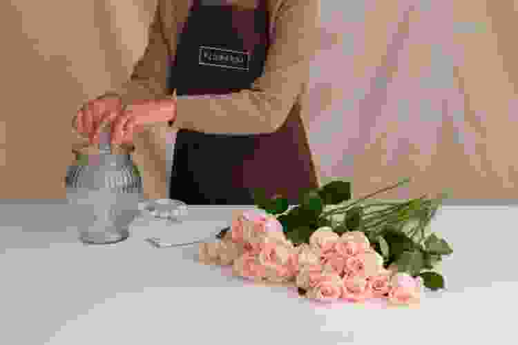 hands arranging flowers into vase