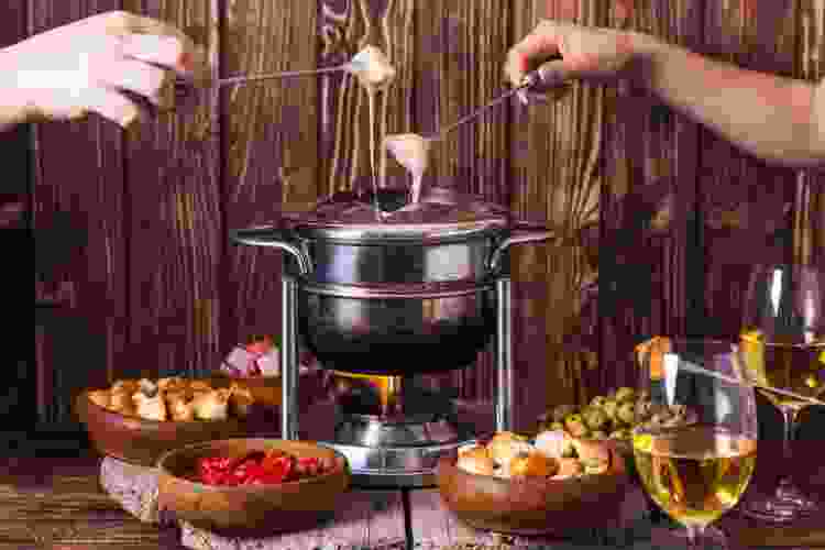 hands dipping food in fondue 