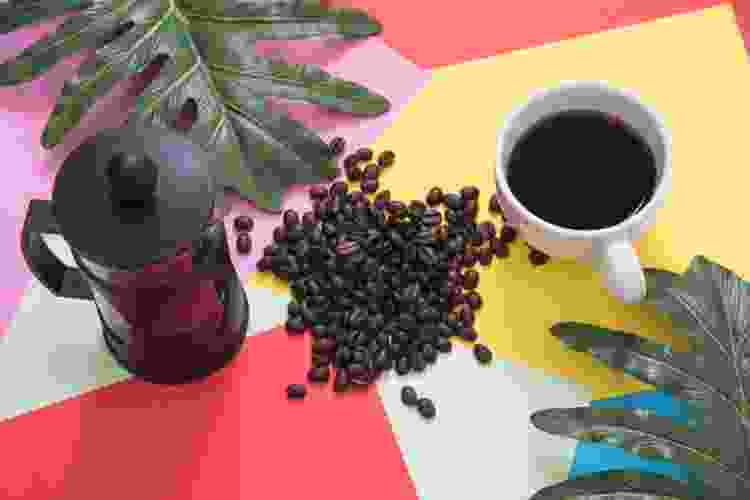 French press and coffee beans on colorful table