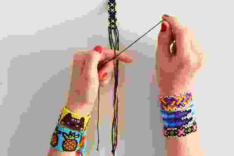 hands wearing friendship bracelets while making friendship bracelets