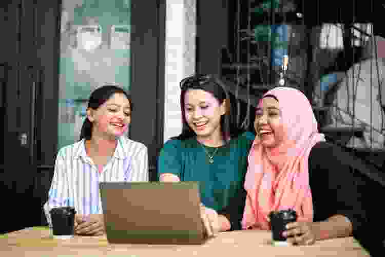 women playing games on laptop outside