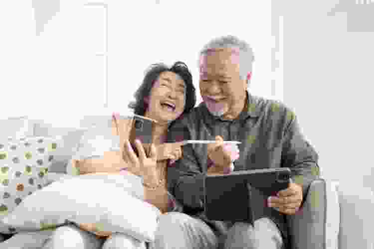 older couple laughing while playing games on tablet