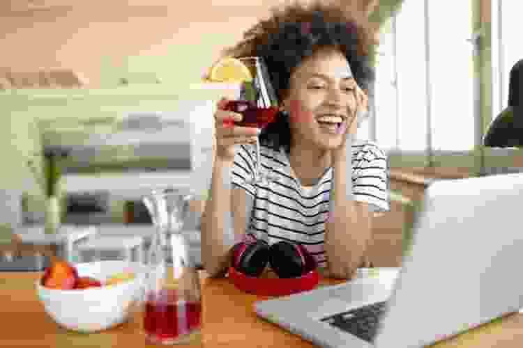 woman drinking sangria will face-timing on laptop