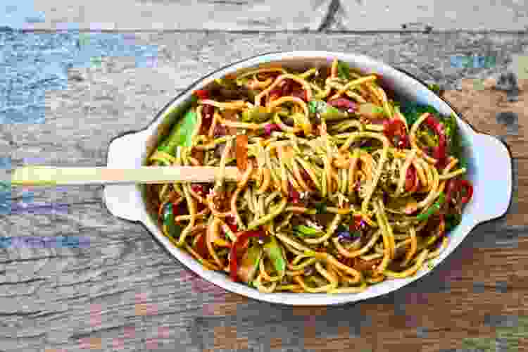 chopsticks and dish of ginger noodles and vegetables