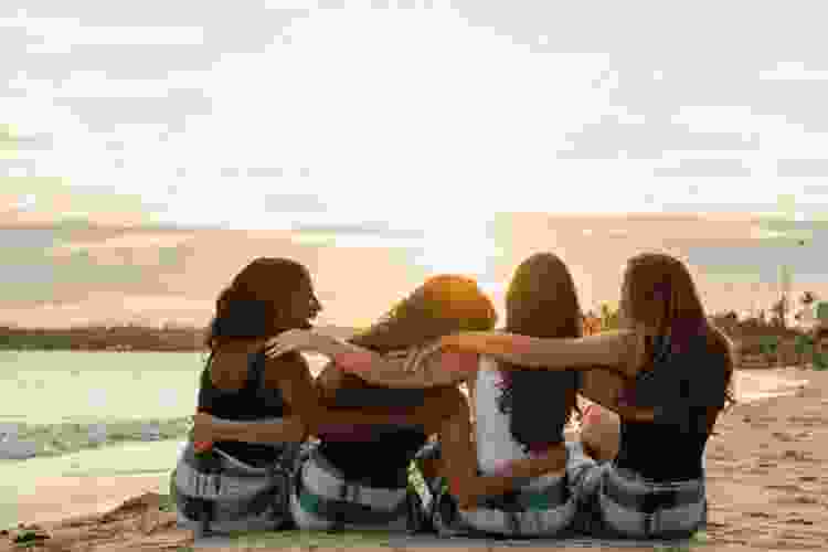 four girlfriends watching sunset together at the beach