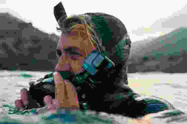 man in wetsuit using underwater camera at the beach