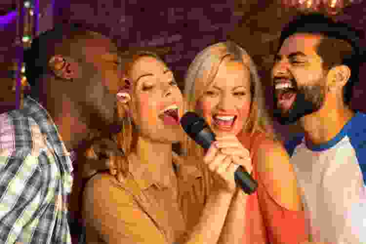 group of young people singing into karaoke mic