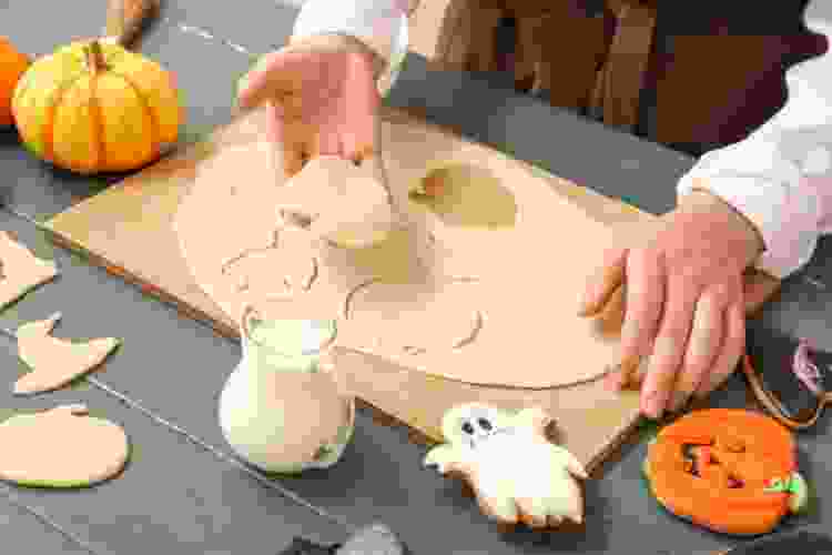 hands cutting out cookie dough in Halloween shapes