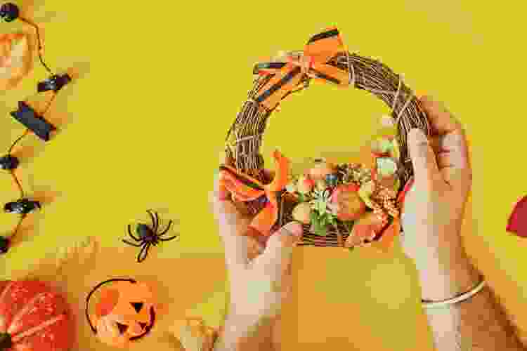 hands assembling orange wreath Halloween craft idea