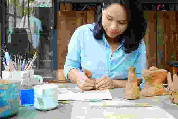 woman at table outdoors hand building pottery molding clay