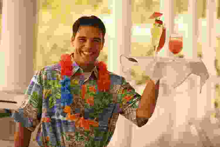 man in lei and Hawaiian shirt holding tray of tropical cocktails