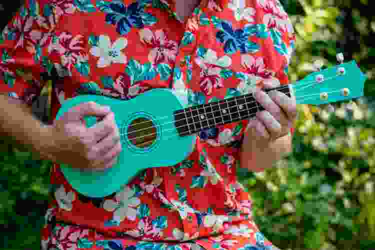 man in floral Hawaiian shirt playing teal ukelele