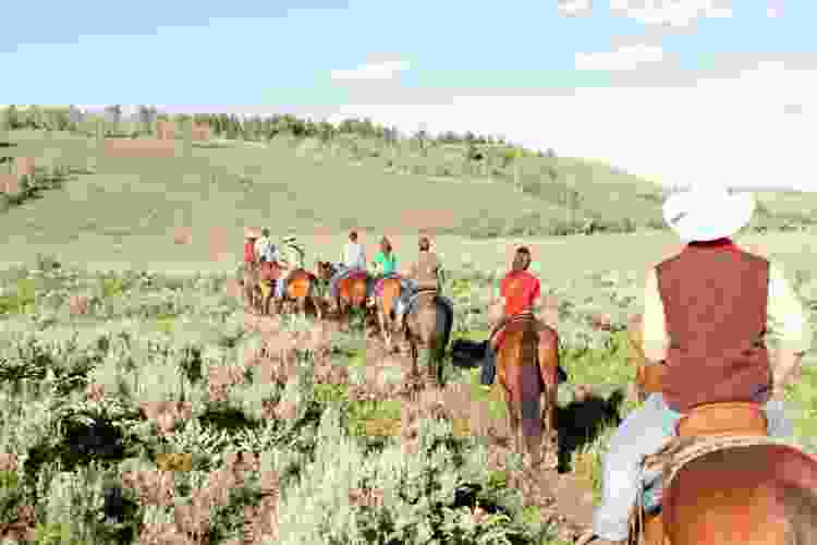 large group riding horses in the mountains