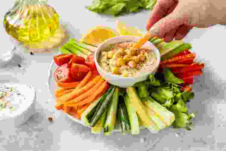 bowl of hummus surrounded by colorful vegetable sticks