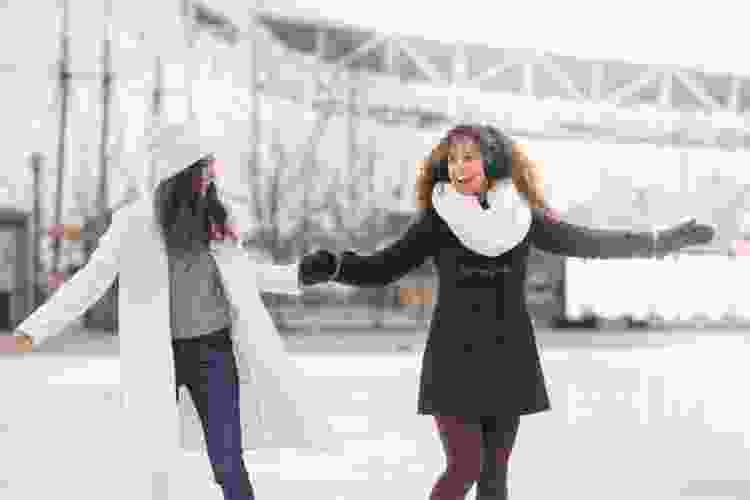 two women ice skating together in rink