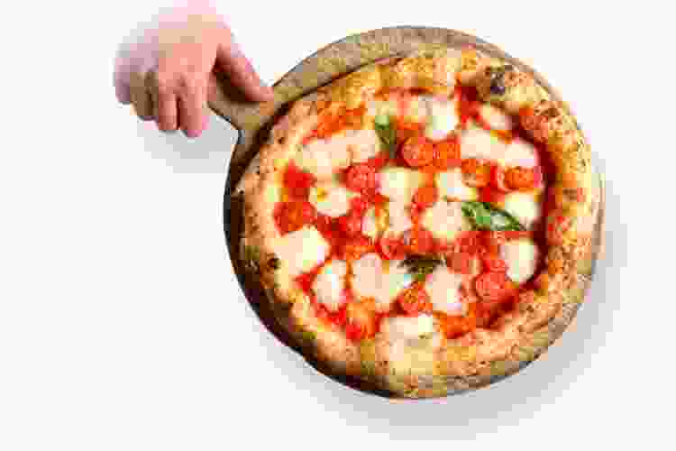 Kesté Pizza e Vino with hand holding tomato pizza on pan