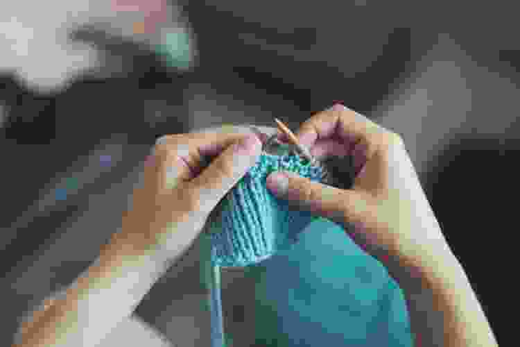 hands knitting blue yarn