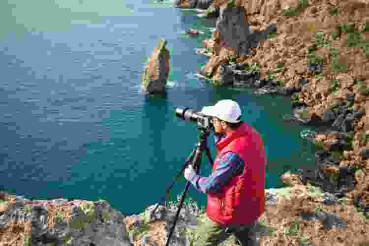 photographer standing on cliff with camera