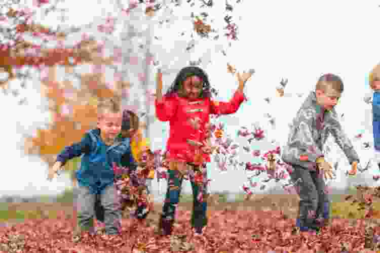 kids jumping in fall leaf pile