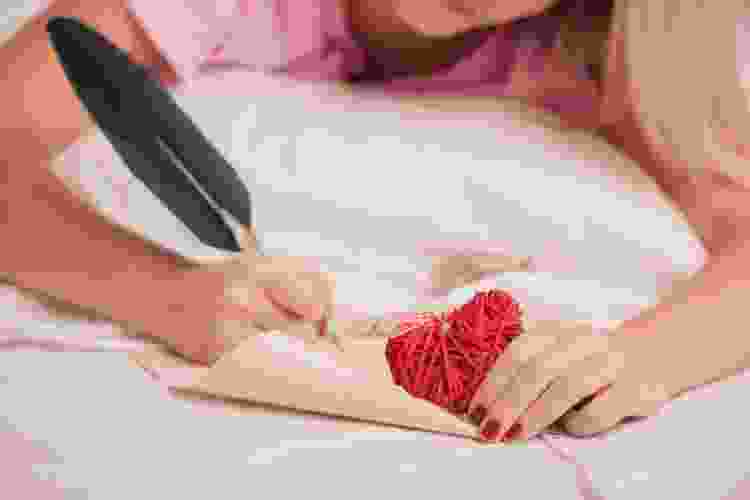 young woman writing a love letter with a feather pen