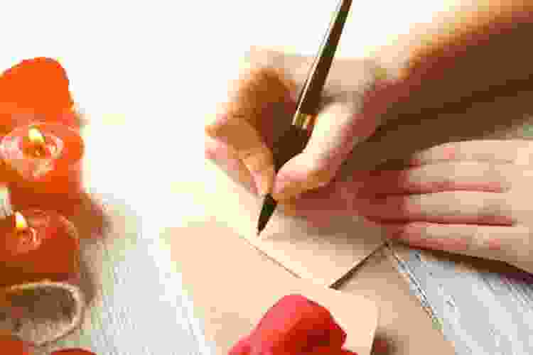 hand writing a love letter on stationary