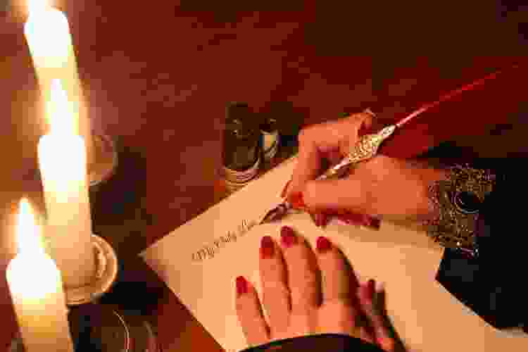 hand writing love letter by candlelight 