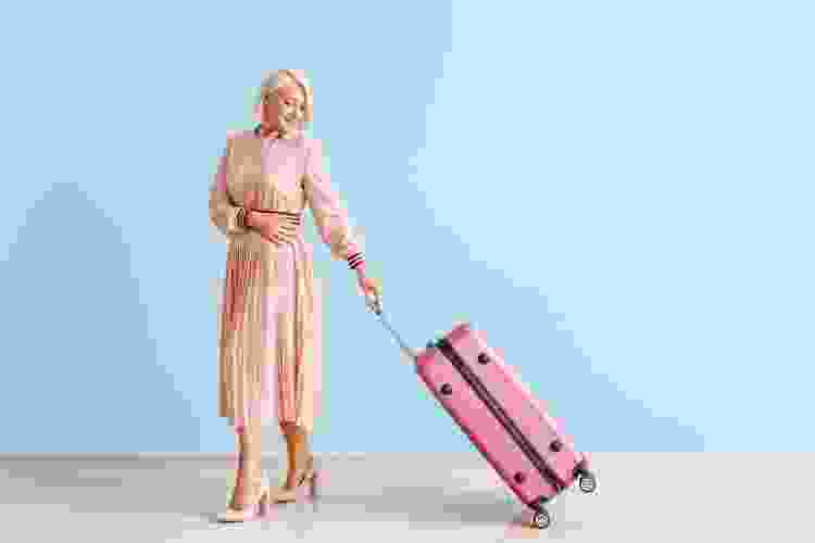 woman in pink dress carrying matching pink luggage