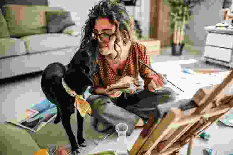 woman painting on the floor with her dog