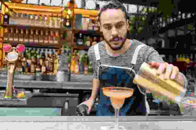 mixologist pouring cocktail in glass