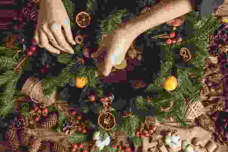 making holiday wreath with ribbon and pinecones